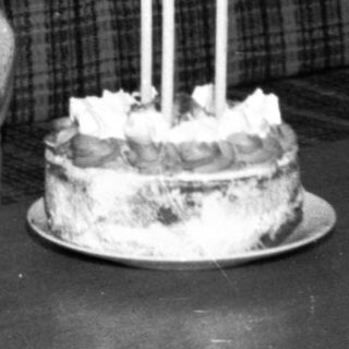 Young child sitting with birthday cake and lit candles.