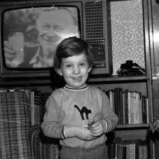 A woman and young boy posing indoors near old TV.