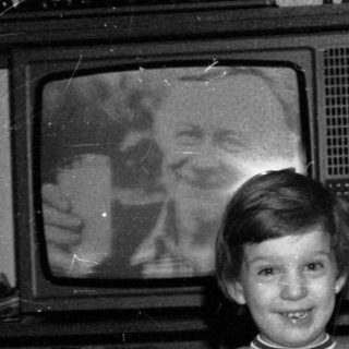 A woman and young boy posing indoors near old TV.
