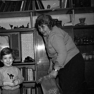 A woman and young boy posing indoors near old TV.