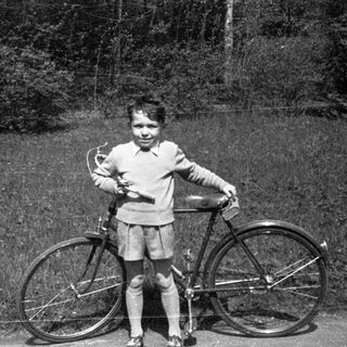 Child posing with vintage bicycle outdoors.