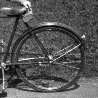 Child posing with vintage bicycle outdoors.