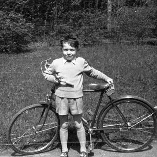 Child posing with vintage bicycle outdoors.