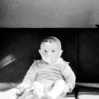 Baby sitting indoors on a bed.