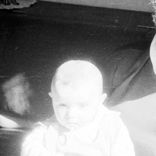 Blurred indoor scene with two people, one wearing curly hair.
