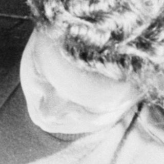 Blurred indoor scene with two people, one wearing curly hair.