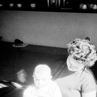 Blurred indoor scene with two people, one wearing curly hair.