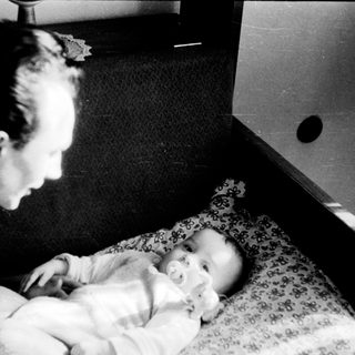 A man tenderly holds a sleeping baby indoors.