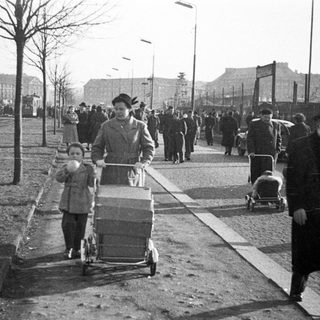 People crossing divided Berlin checkpoint area.