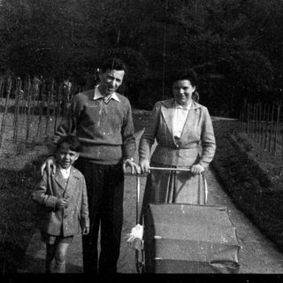 Family walking with baby buggy outdoors.