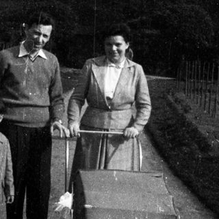 Family walking with baby buggy outdoors.