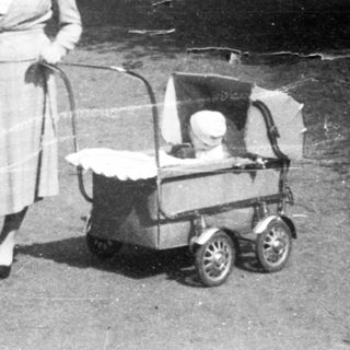 Couple pushing baby stroller in wooded area.