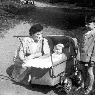 Family outing with woman pushing baby stroller, older child standing beside them.