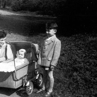 Family outing with woman pushing baby stroller, older child standing beside them.