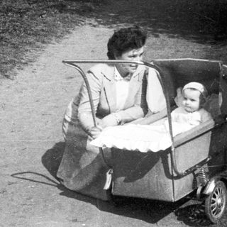 Family outing with woman pushing baby stroller, older child standing beside them.