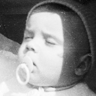 Sleeping infant in vintage crib with pacifier.