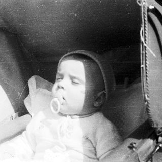 Sleeping infant in vintage crib with pacifier.
