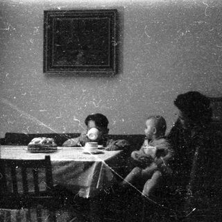 Family meal scene in vintage indoor setting.