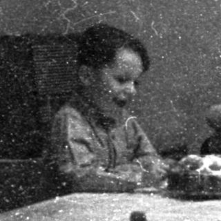 Two children eating at a small table indoors.