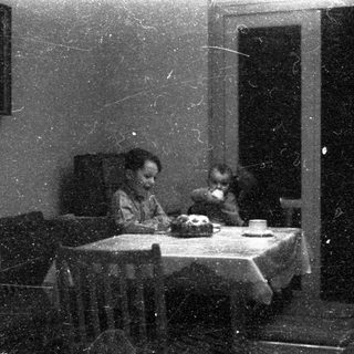 Two children eating at a small table indoors.