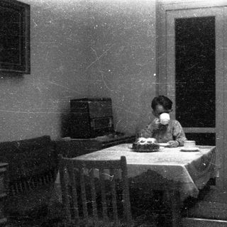 Child drinking tea at a small table indoors.