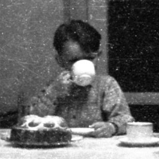 Child drinking tea at a small table indoors.