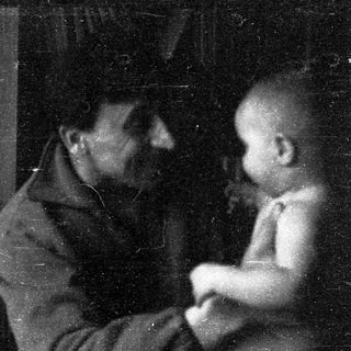 A man and child sitting closely indoors.