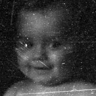 A blurred black-and-white photo of an infant being held.
