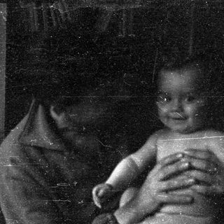 A blurred black-and-white photo of an infant being held.