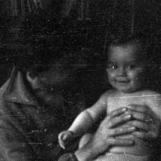 A blurred black-and-white photo of an infant being held.