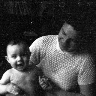 A woman holding a smiling infant indoors.