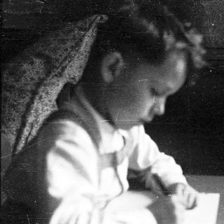 Child writing at a table indoors.
