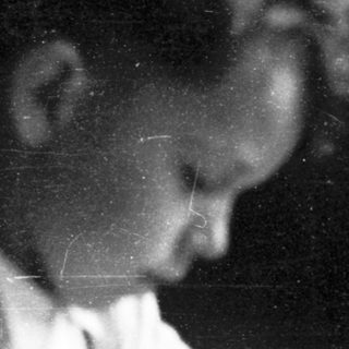 Child writing at a table indoors.