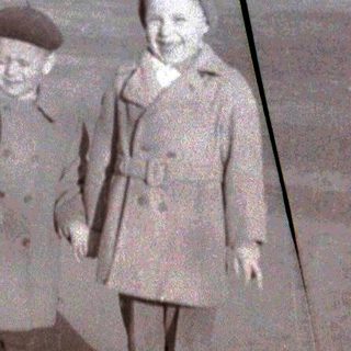 Two children posing together outdoors in vintage clothing.