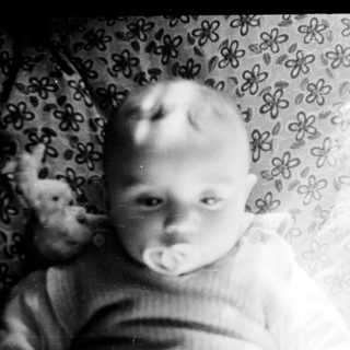 Baby in vintage photo with teddy bear.