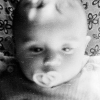 Baby in vintage photo with teddy bear.