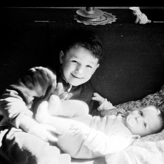 Two boys holding and smiling with a baby.