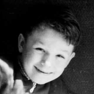 Two boys holding and smiling with a baby.