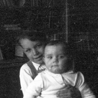 Two children indoors, one holding the other.