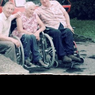 Family posing outside residential building with wheelchair.