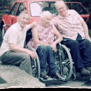 Family posing outside residential building with wheelchair.