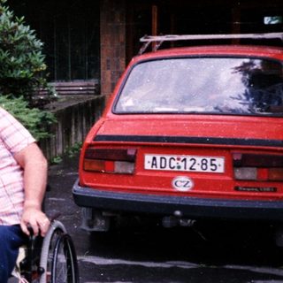 Three elderly individuals in wheelchairs posing outdoors.