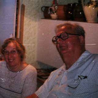 Four people smiling indoors near open window.