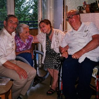 Four elderly people smiling together indoors.