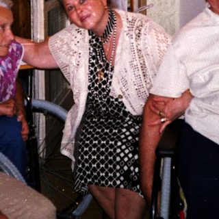 Four elderly people posing happily indoors near a window.
