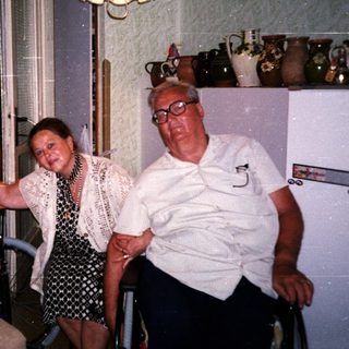 Four elderly people posing happily indoors near a window.