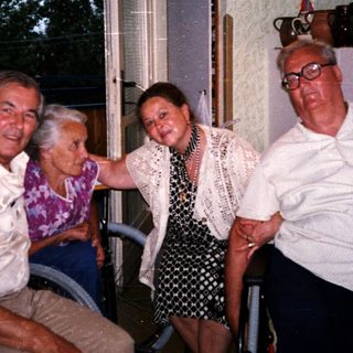Four elderly people posing happily indoors near a window.