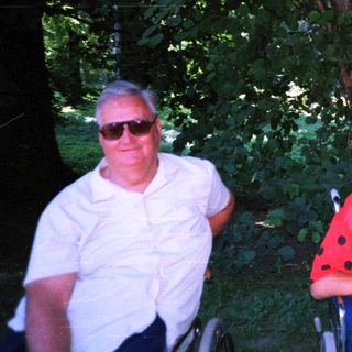 Four adults posing together outdoors in casual attire.