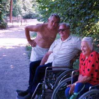 Four elderly individuals posing outdoors in a park.