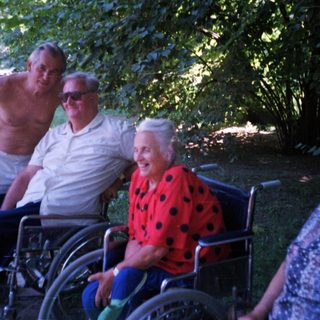 Four elderly individuals posing outdoors in a park.